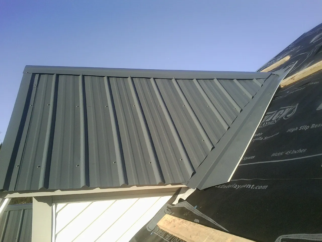Gray metal roof panels going on over a garage gable in Fallentimber