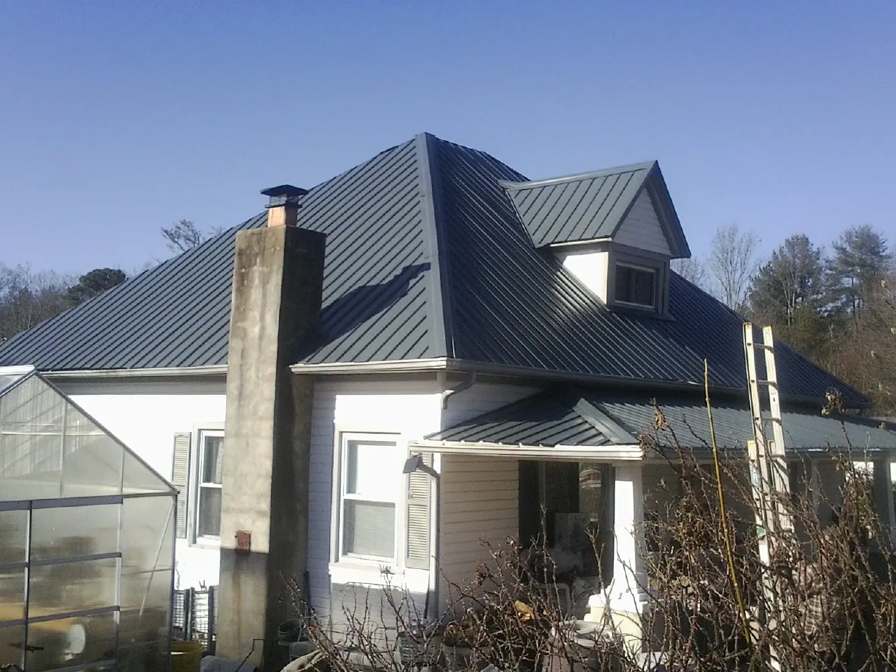 Dark blue standing seam metal roof on a white farmhouse with dormer — Slate & Tile Roof Repair by Roofing Brothers in Fallentimber