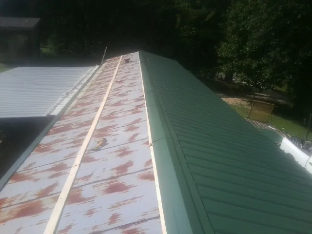 Old rusted panels beside newly installed green metal roofing — Wind Damage Roof Repair by Roofing Brothers in Fallentimber