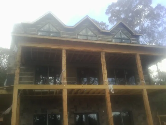 Dormers and porch framing on a large log home under construction — Roof Coating work by our crew in Fallentimber