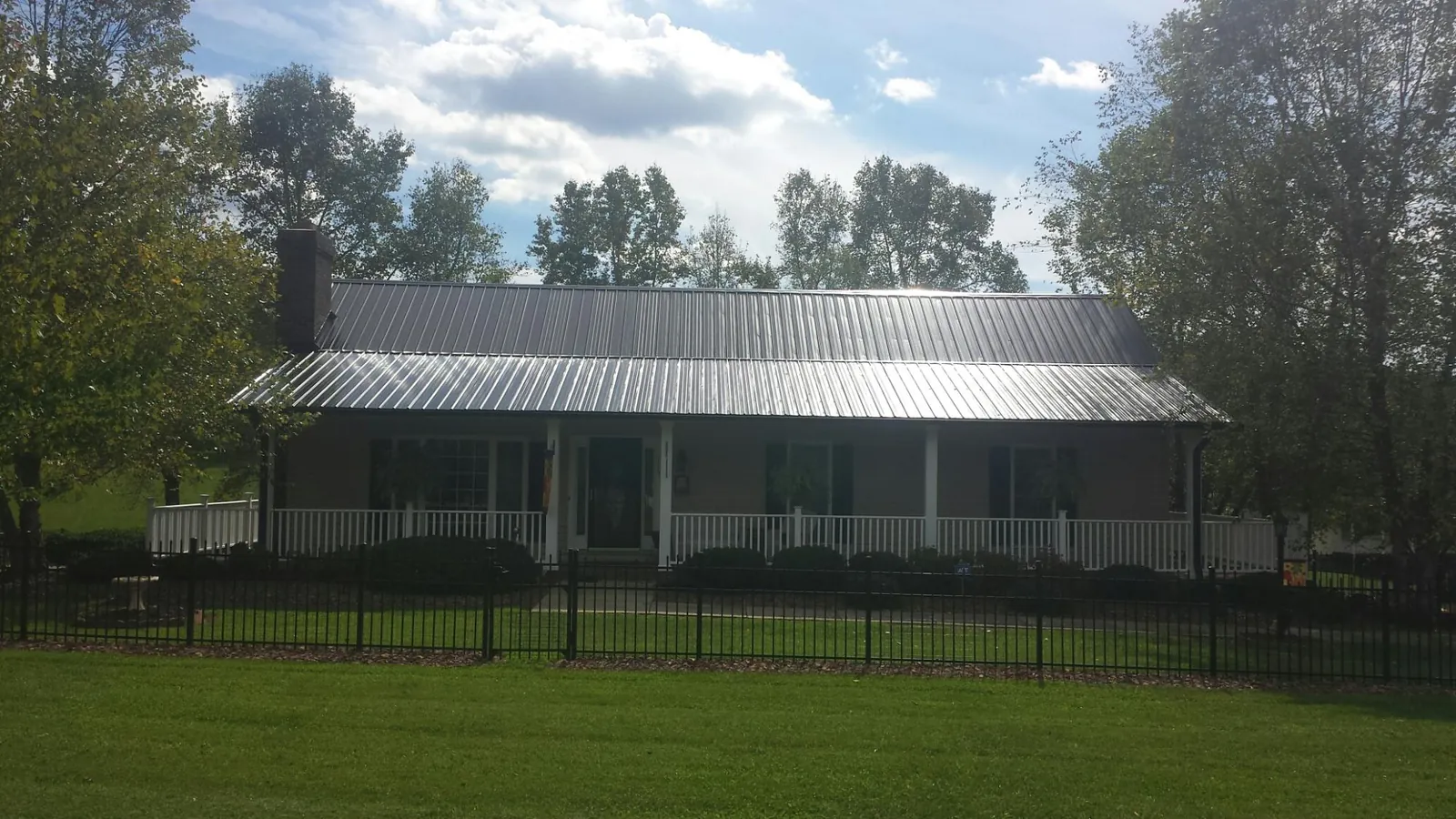 Gray metal roof on a brick ranch with a full width front porch — Gutter Guard Installation work by our crew in Fallentimber